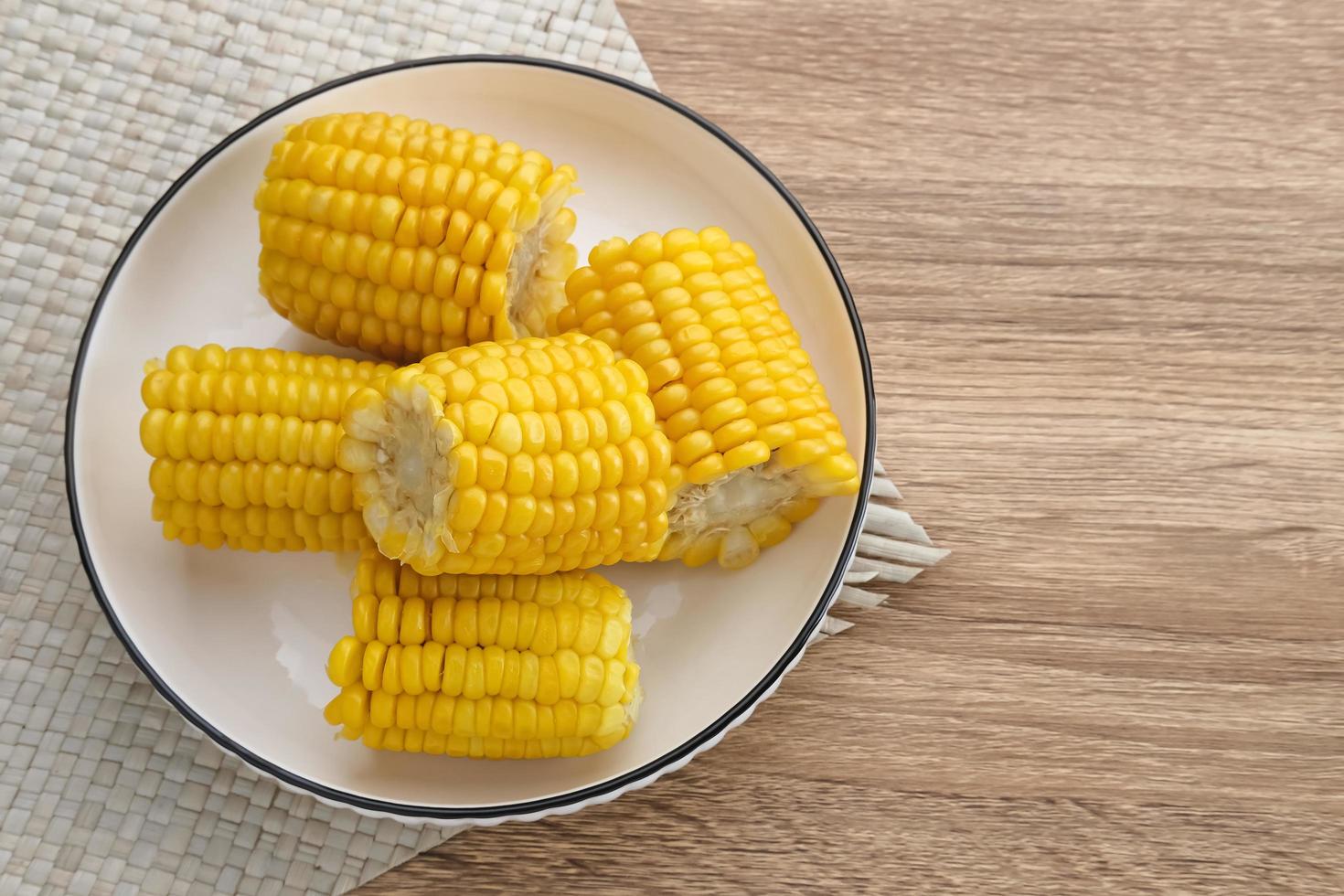 Jagung manis rebus or boiled sweet corn slices served on bowl on wooden background. Space for text. photo