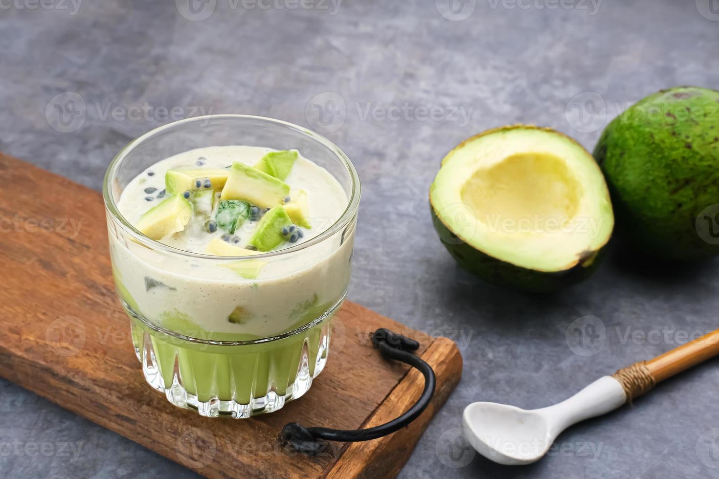 El postre de queso con leche de aguacate está hecho de aguacate, gelatina, queso, semillas de albahaca, leche condensada azucarada y leche evaporada. servido en un vaso. espacio para texto foto