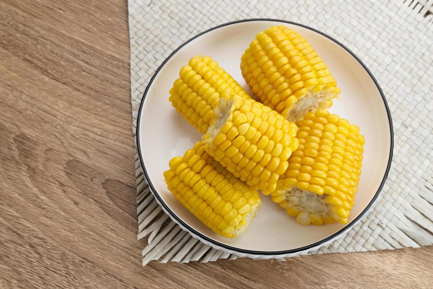 Jagung manis rebus or boiled sweet corn slices served on bowl on wooden background. Space for text. photo