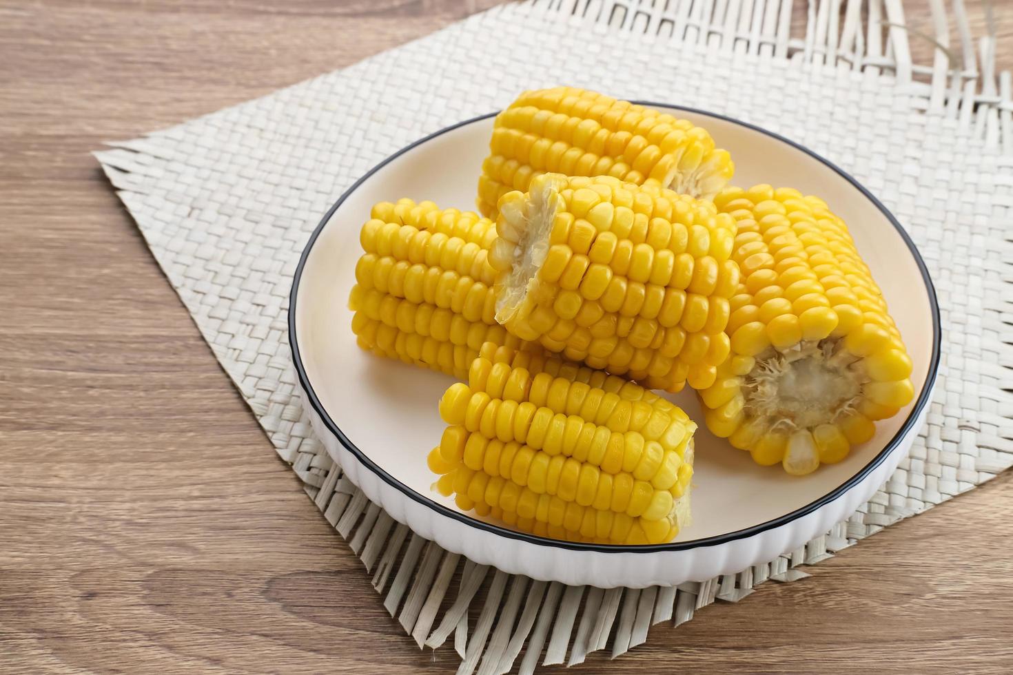 Jagung manis rebus or boiled sweet corn slices served on bowl on wooden background. Space for text. photo