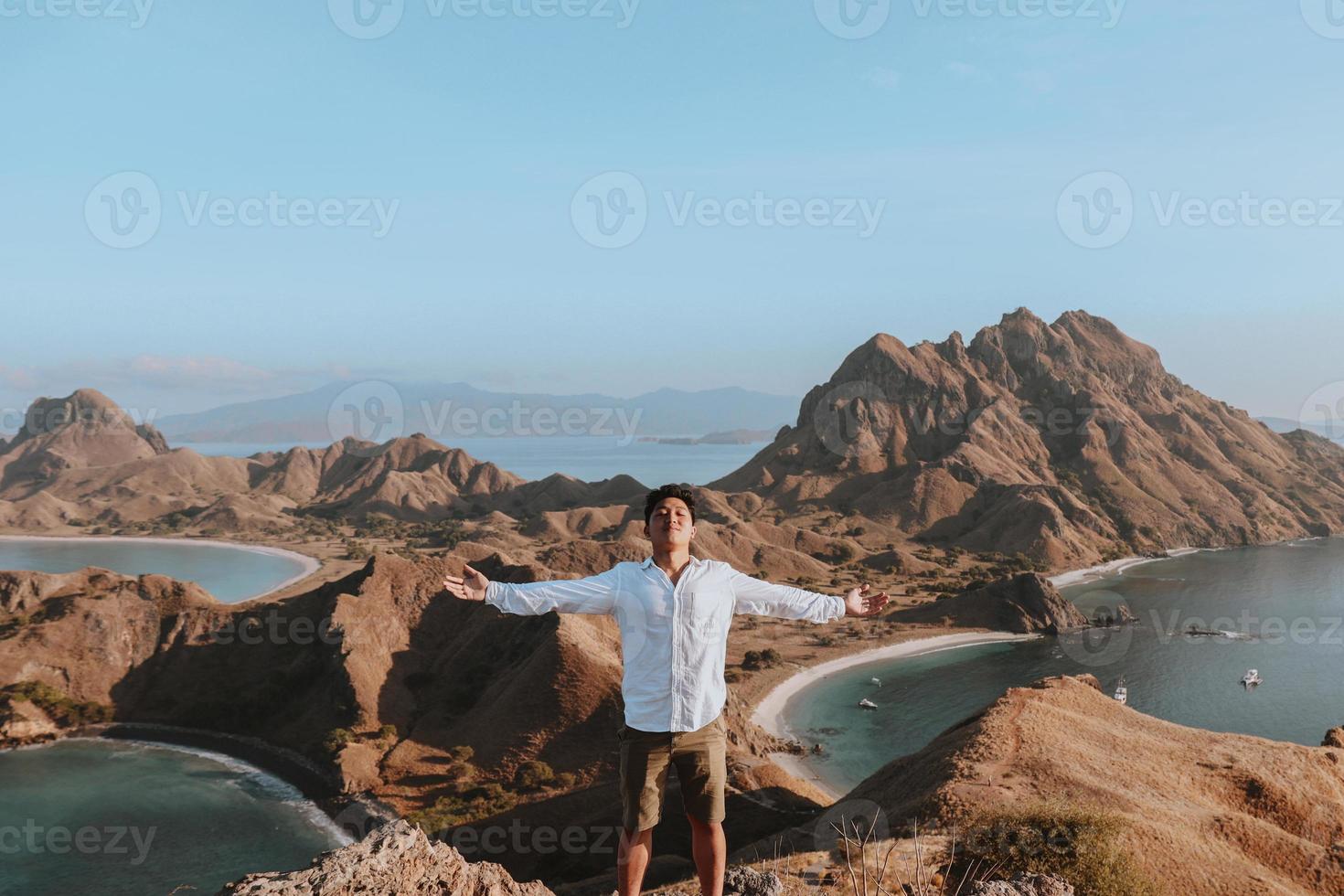Happy Asian man standing on the top hill of Padar Island photo