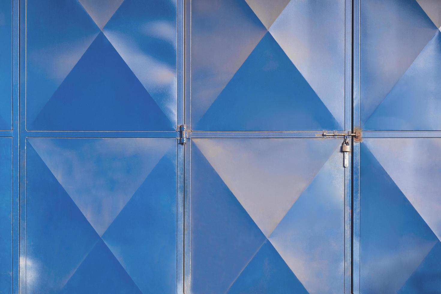 Light reflection on rhombus pattern surface of the old steel folding gate door of machine shop photo