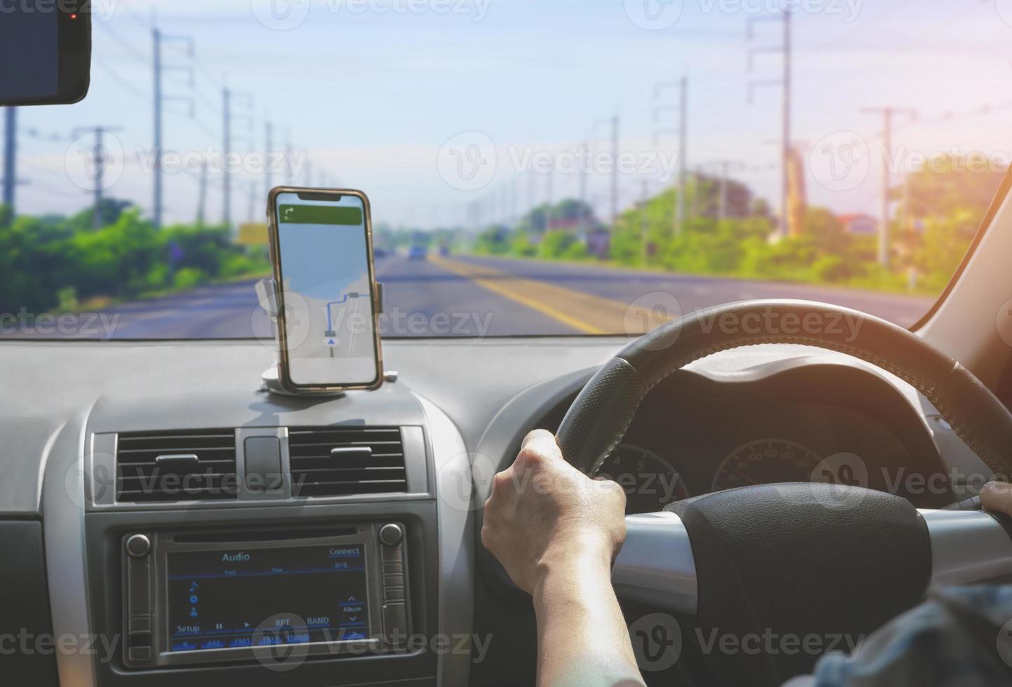 conductor de automóvil que usa un teléfono inteligente con una aplicación de navegación de mapas gps mientras conduce en la autopista, vista desde el interior del automóvil foto