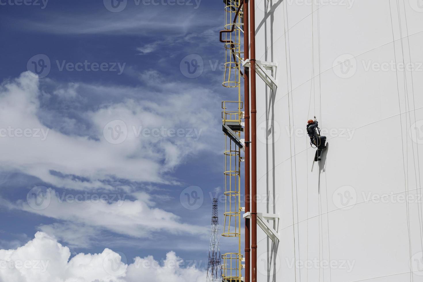 Male workers control swing rope down height tank rope access inspection of thickness pipeline and tank gas. photo