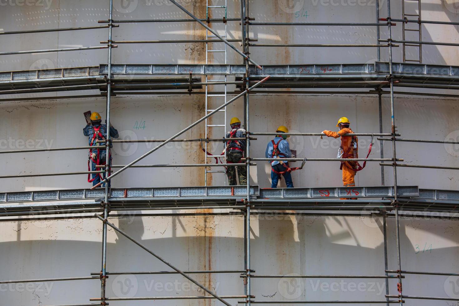 Construction workers tank oil installing scaffolding photo