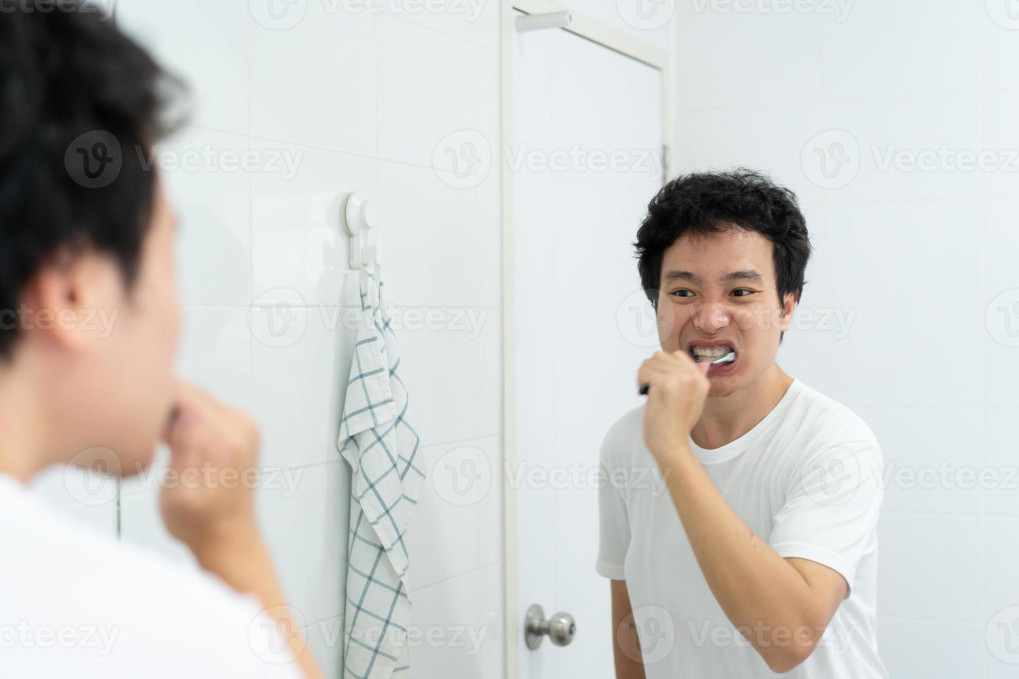 joven asiático cepillándose los dientes. foto