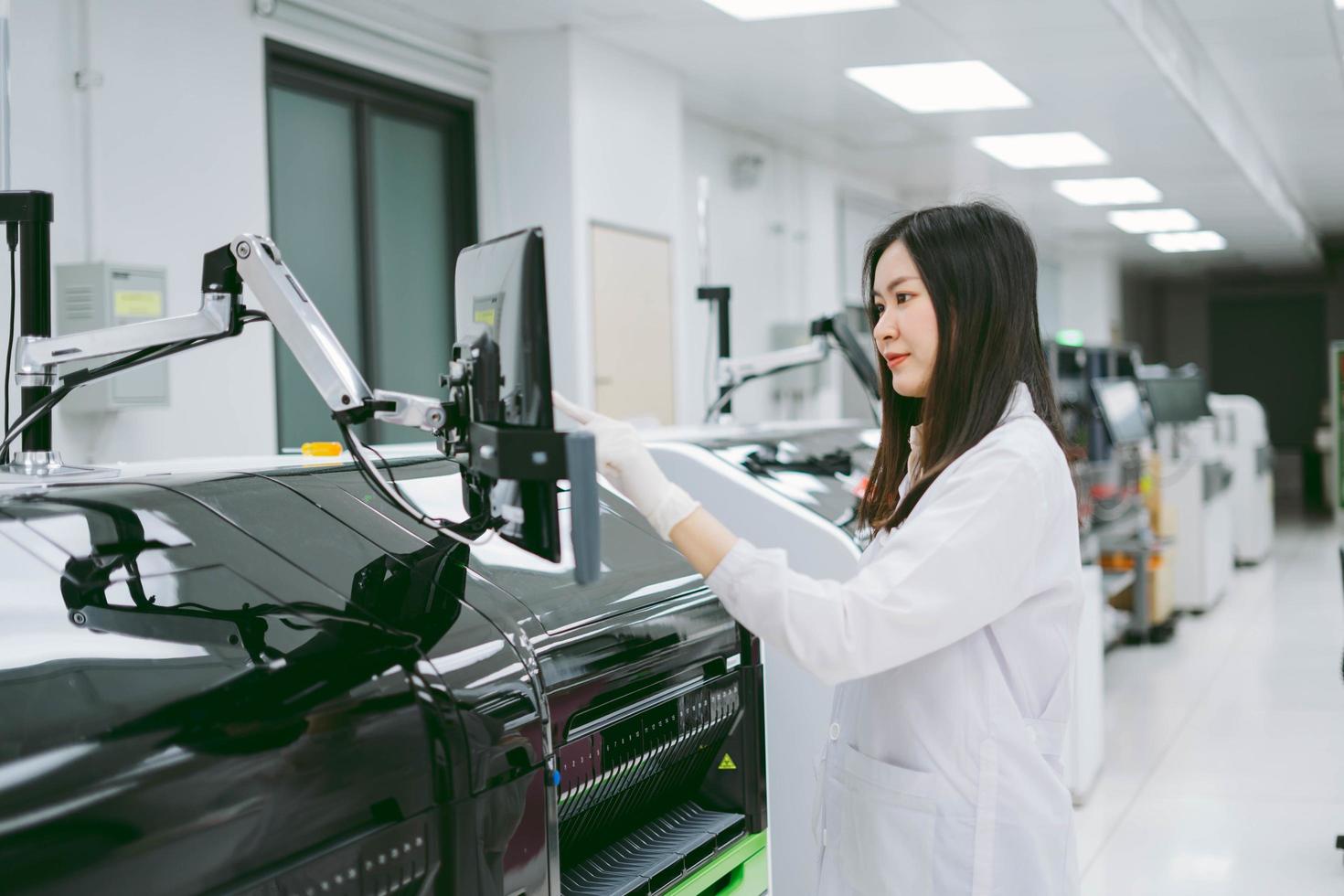 joven científica que trabaja con el informe del analizador de sangre de automatización en el laboratorio médico foto