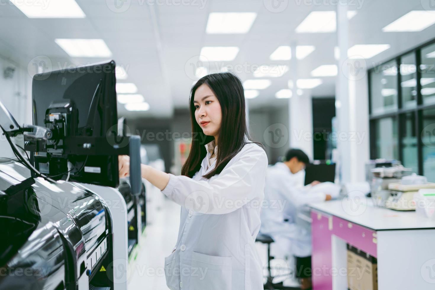 young female scientist working with automation blood analyzer report in medical laboratory photo