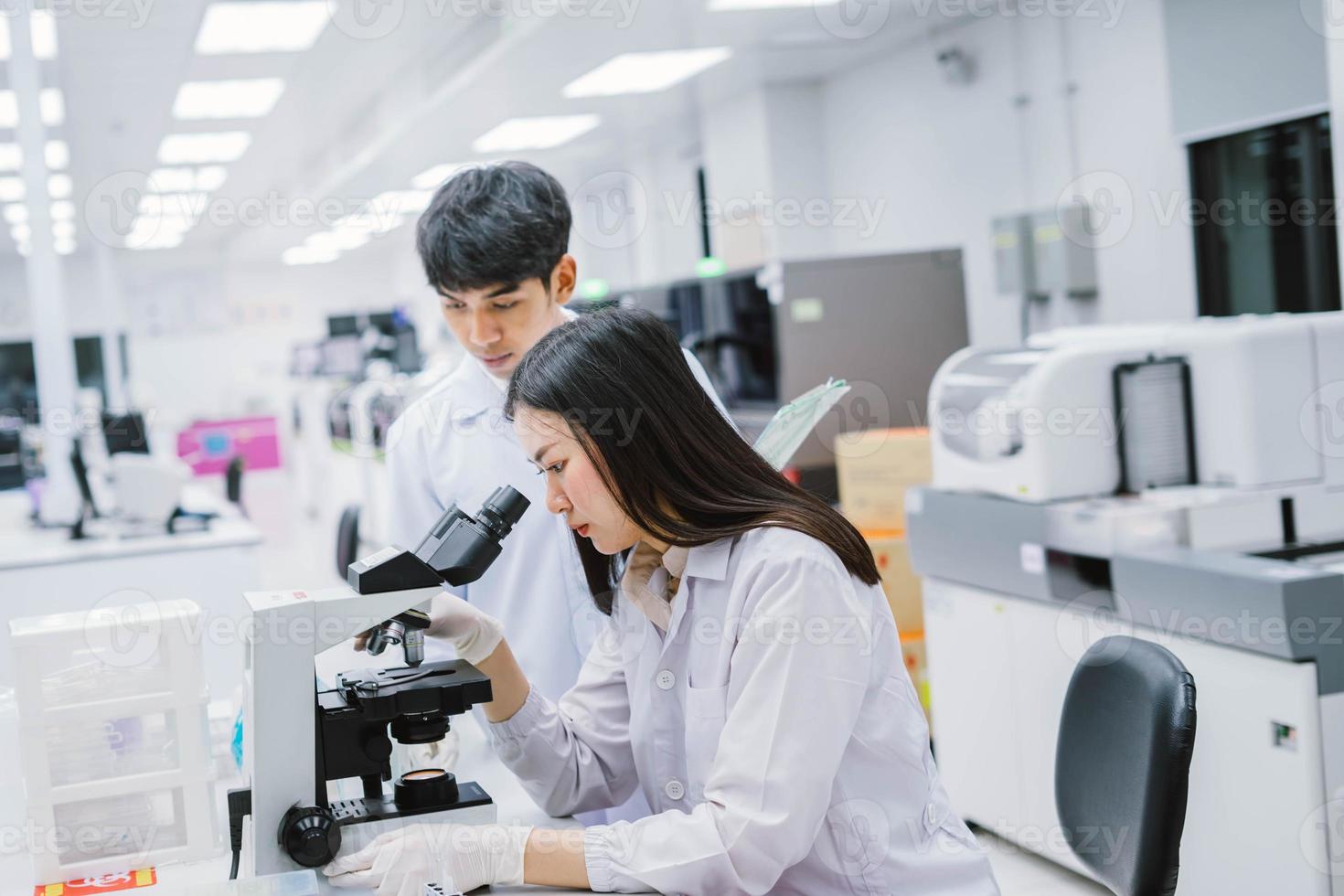 Two medical scientist working in Medical laboratory , young female scientist looking at microscope. select focus in young female scientist photo