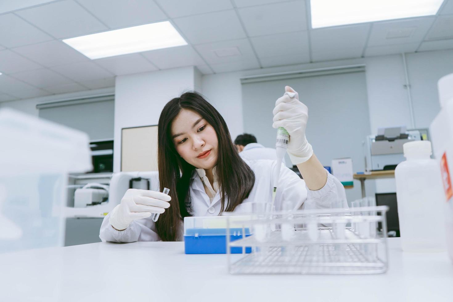 Young medical scientist working in medical laboratory , young female scientist using auto pipette to transfer sample photo