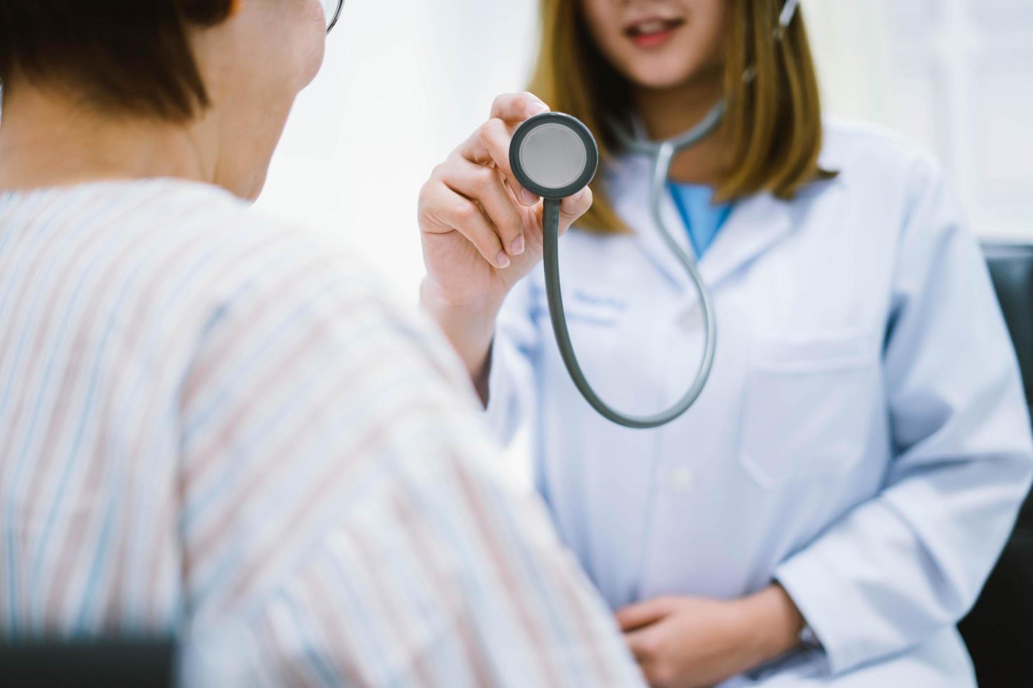 Young doctor using stethoscope to exam senior patient heart photo