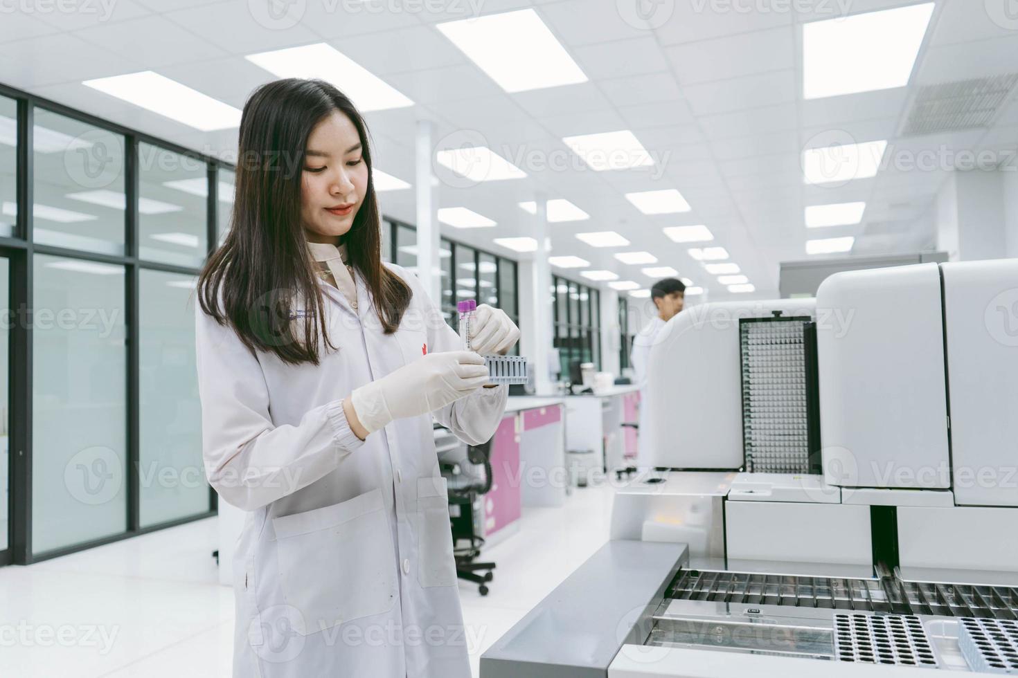 young female scientist working with automation blood analyzer report in medical laboratory photo