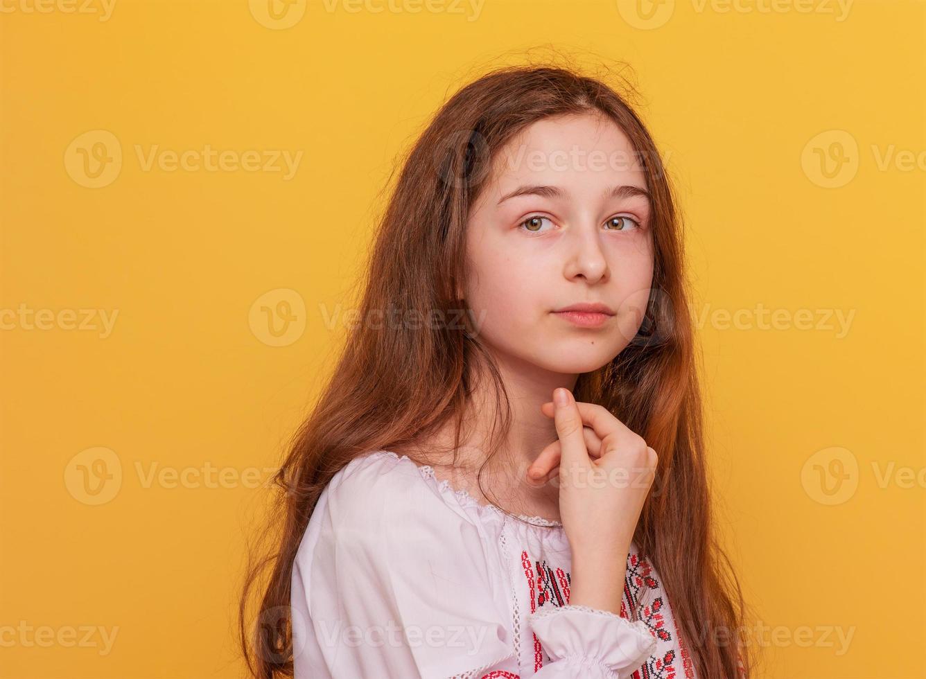 Girl on a yellow background. Portrait of an 11-year-old girl in Ukrainian embroidered clothes. photo