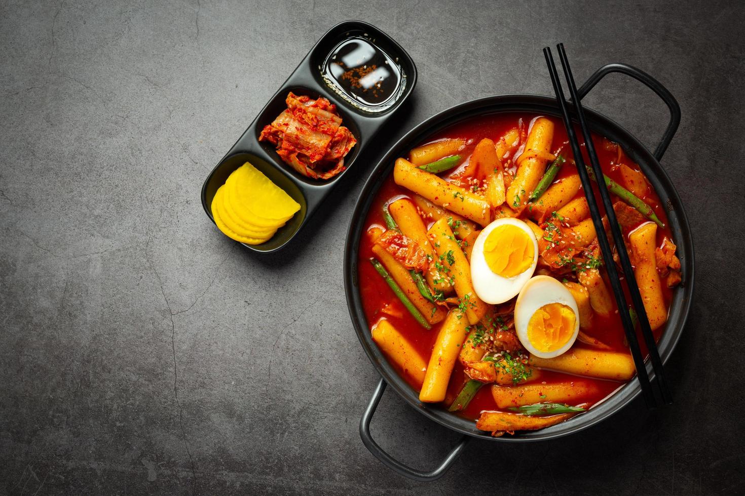 Cheesy Tokbokki korean traditional food on black board background. Lunch dish. photo