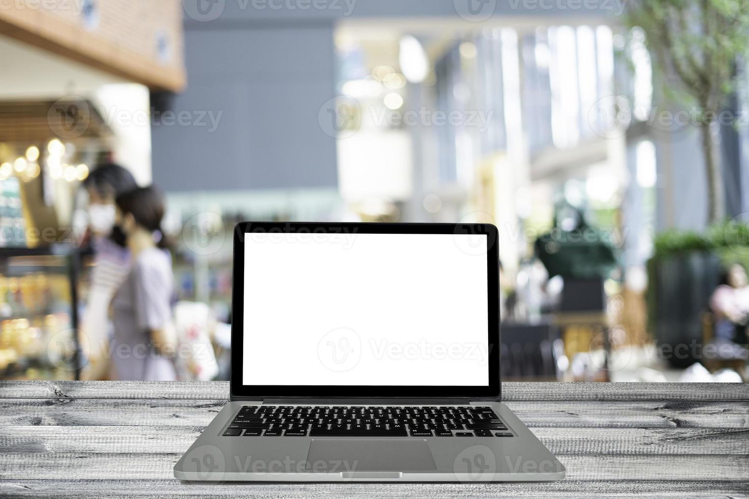 Laptop, computer notebook with blank screen on black wooden with blurred background in the restaurant, warm light tone. photo