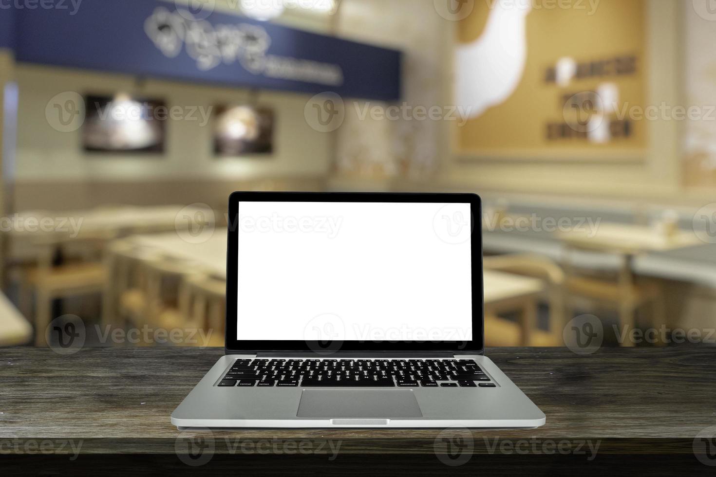 Laptop, computer notebook with blank screen on black wooden with blurred background in the restaurant, warm light tone. photo