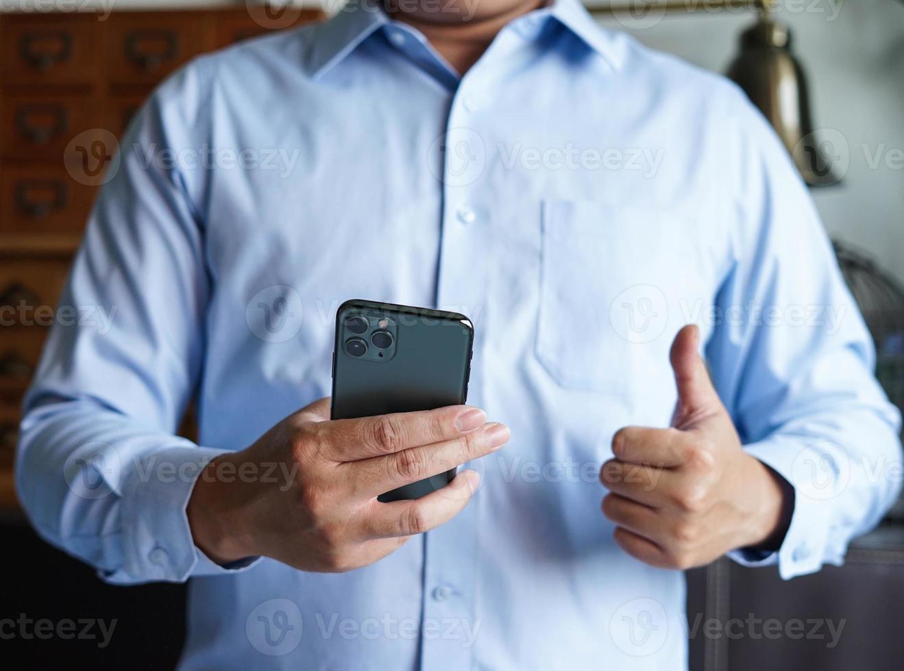 el hombre da un pulgar hacia arriba con el teléfono móvil. foto