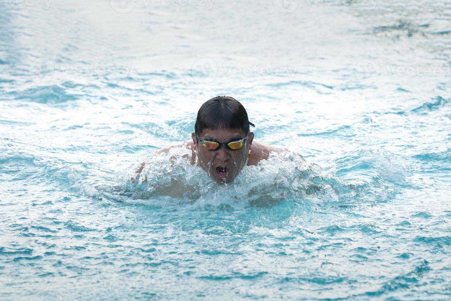 Nadador deportivo con gorra respirando realizando la braza de natación. nadador nadando en la piscina. concepto de natación deportiva. foto