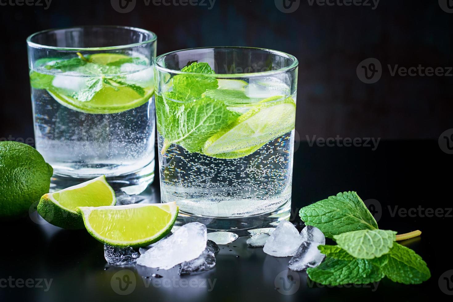 Summer drink lemonade mojito with lime, mint and ice on a black background photo