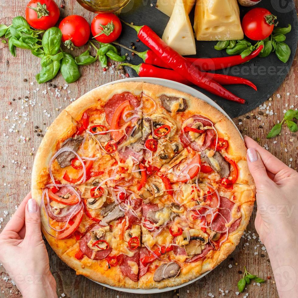 Woman hands takes pizza on a plate, top view photo