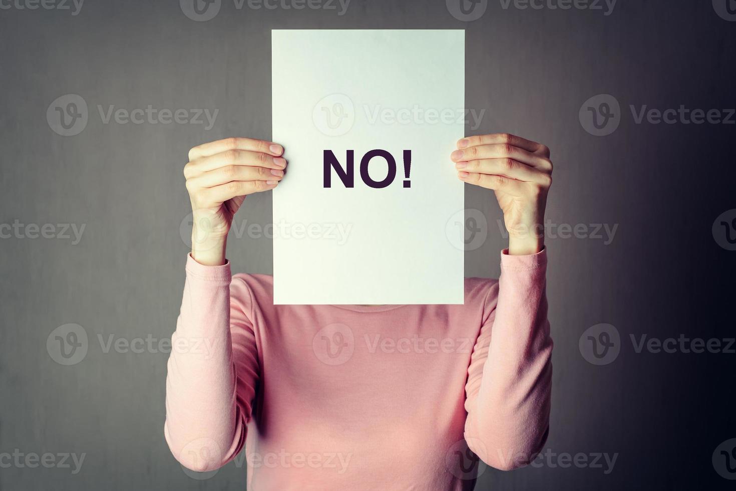 anonymous woman covering face behind a white paper sheet with inscriprion word NO photo