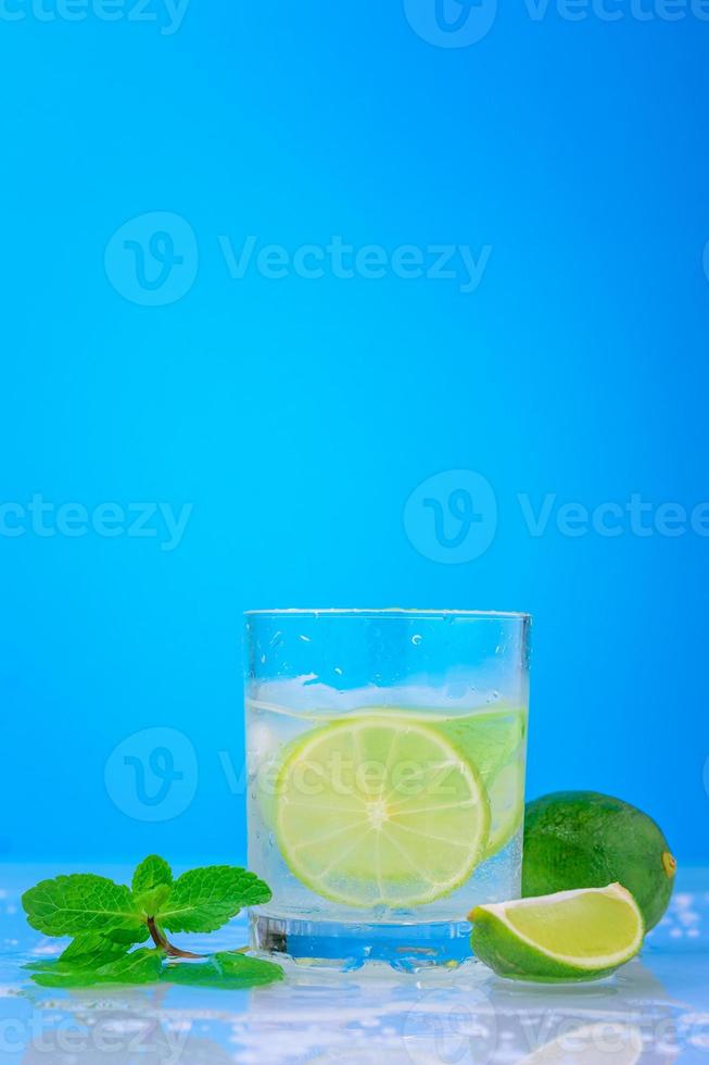 cocktail with lime and fresh mint in glass on a blue background photo