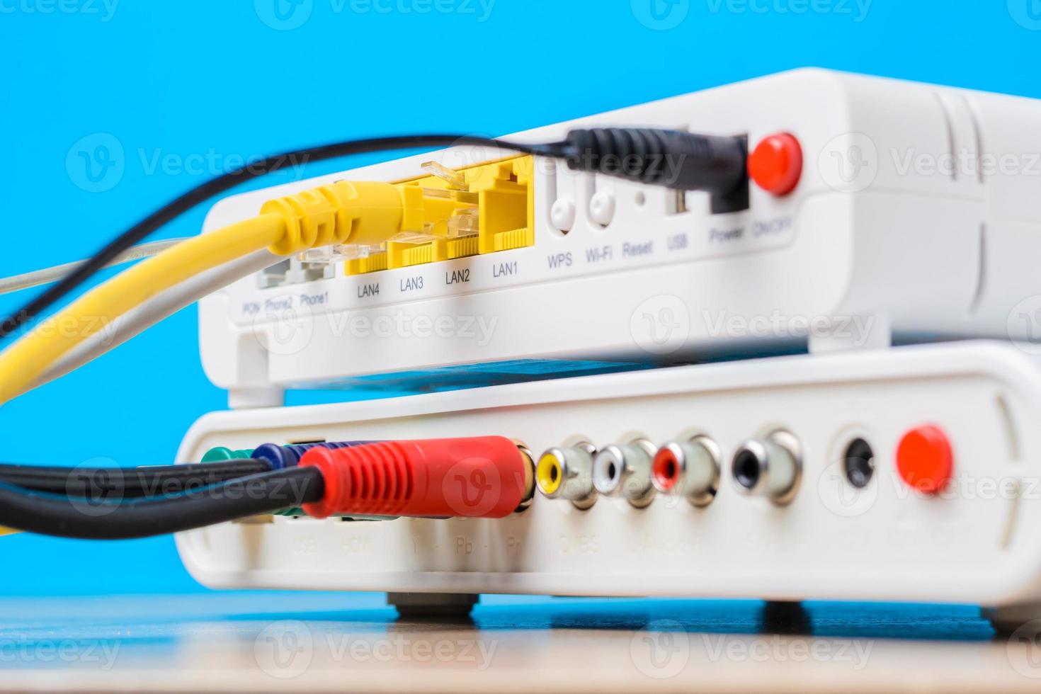 home wireless router with ethernet cables plugged in on blue background, closeup photo