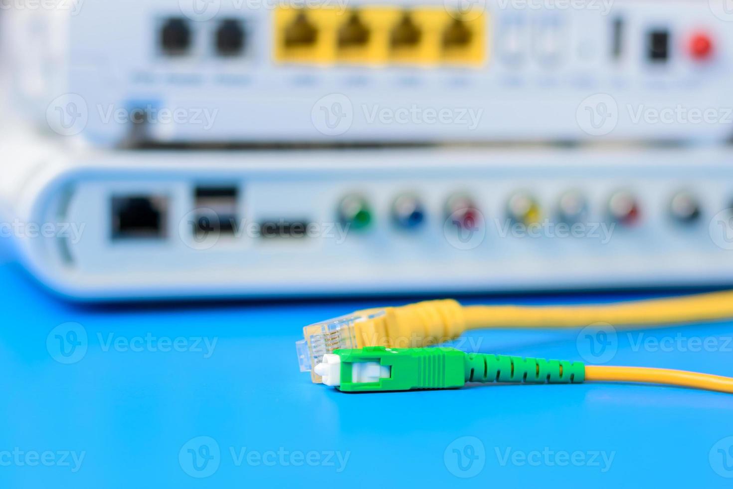 Fiber optical and network cables with internet wireless router on a blue background photo