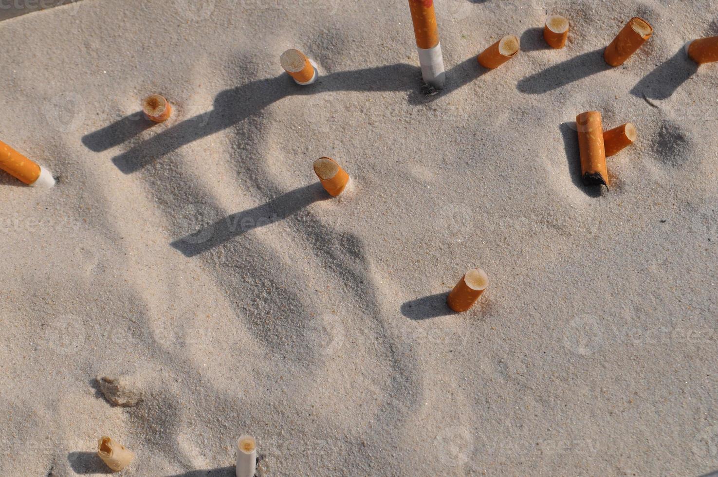 cigarette butts in the sand photo