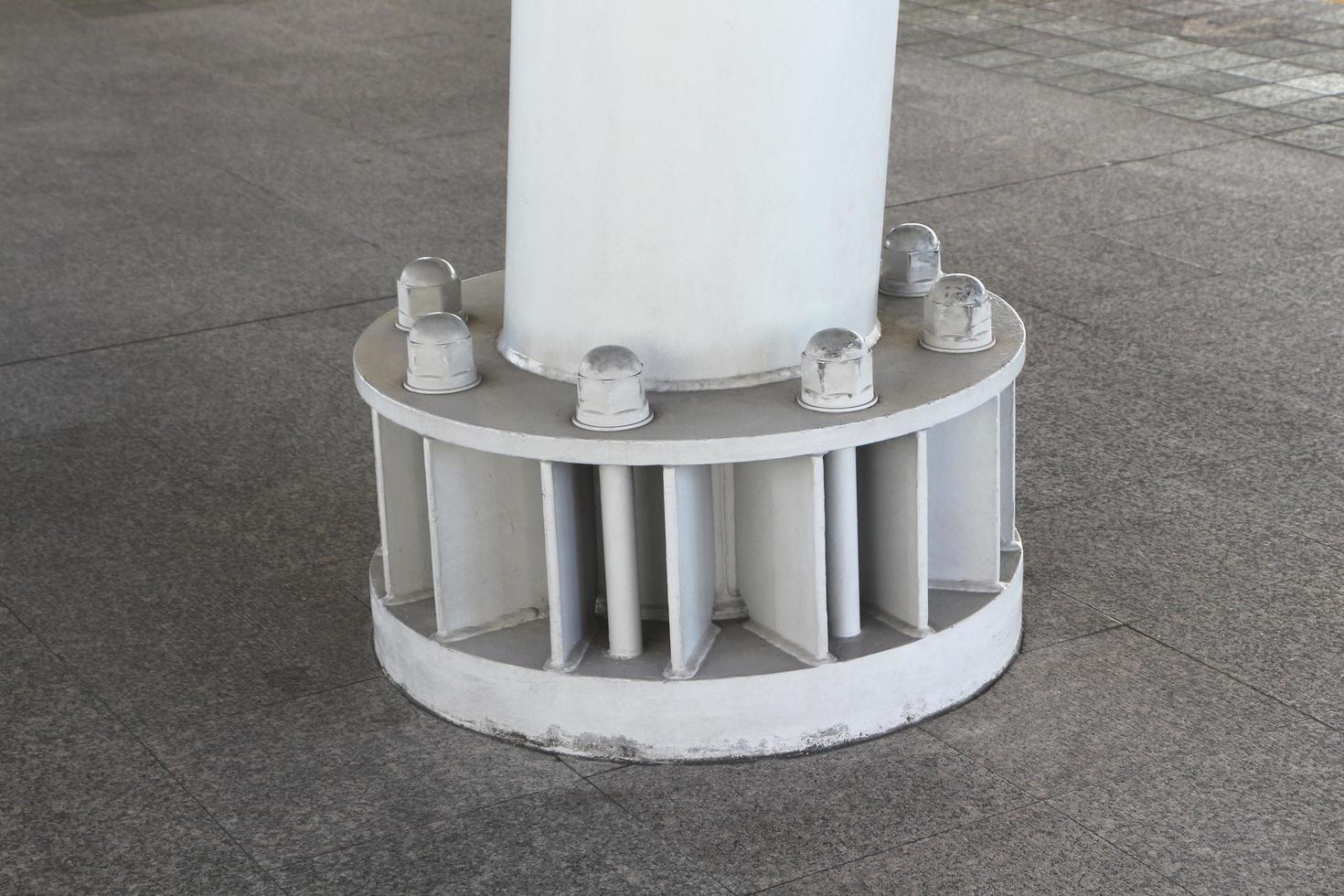 Carbon steel plate and column on the concrete floor. Welded pole to base plate and connecting them to footing with anchor bolts. Studs with heavy hex nut. photo