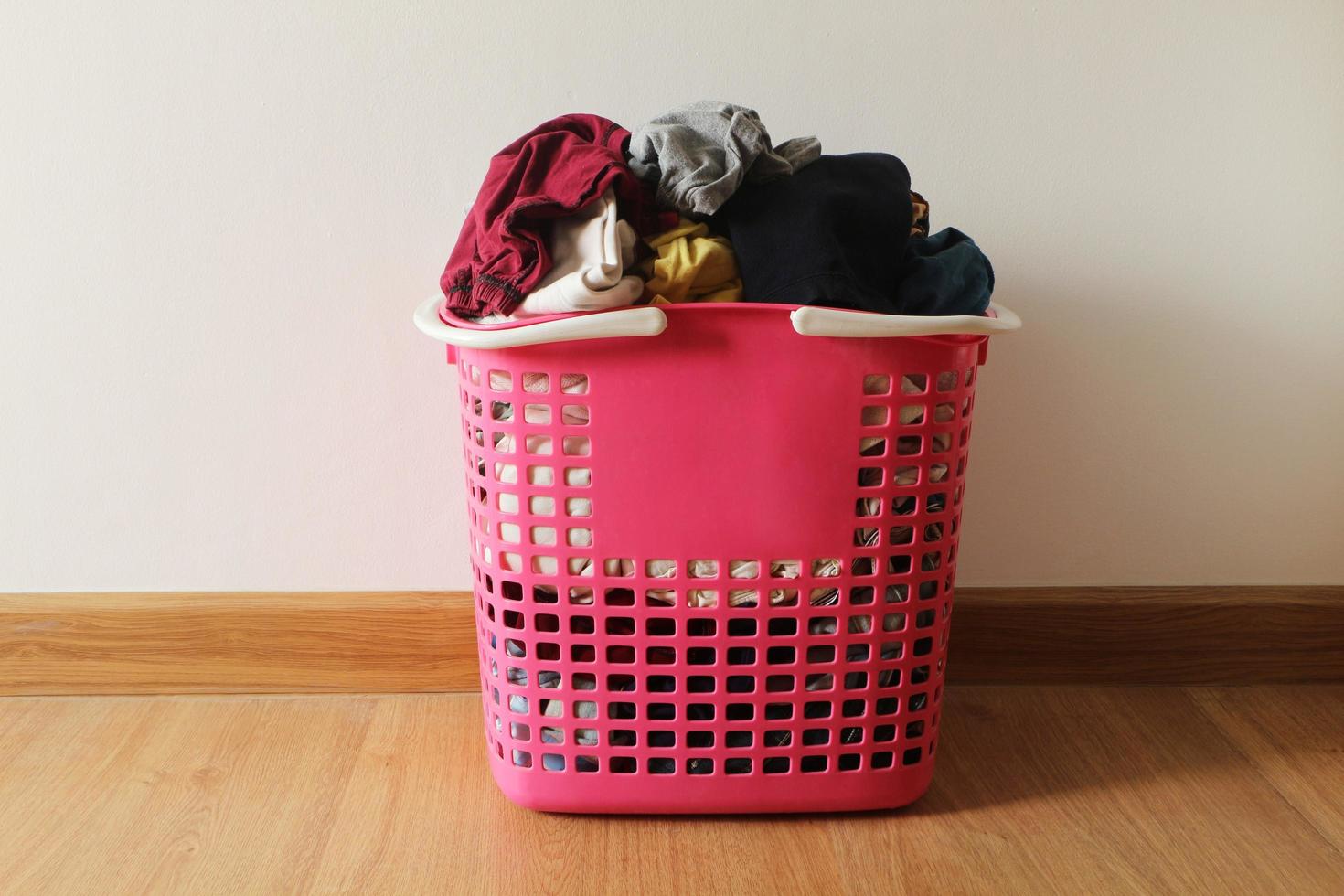 Basket with dirty laundry on the wooden floor in room. photo