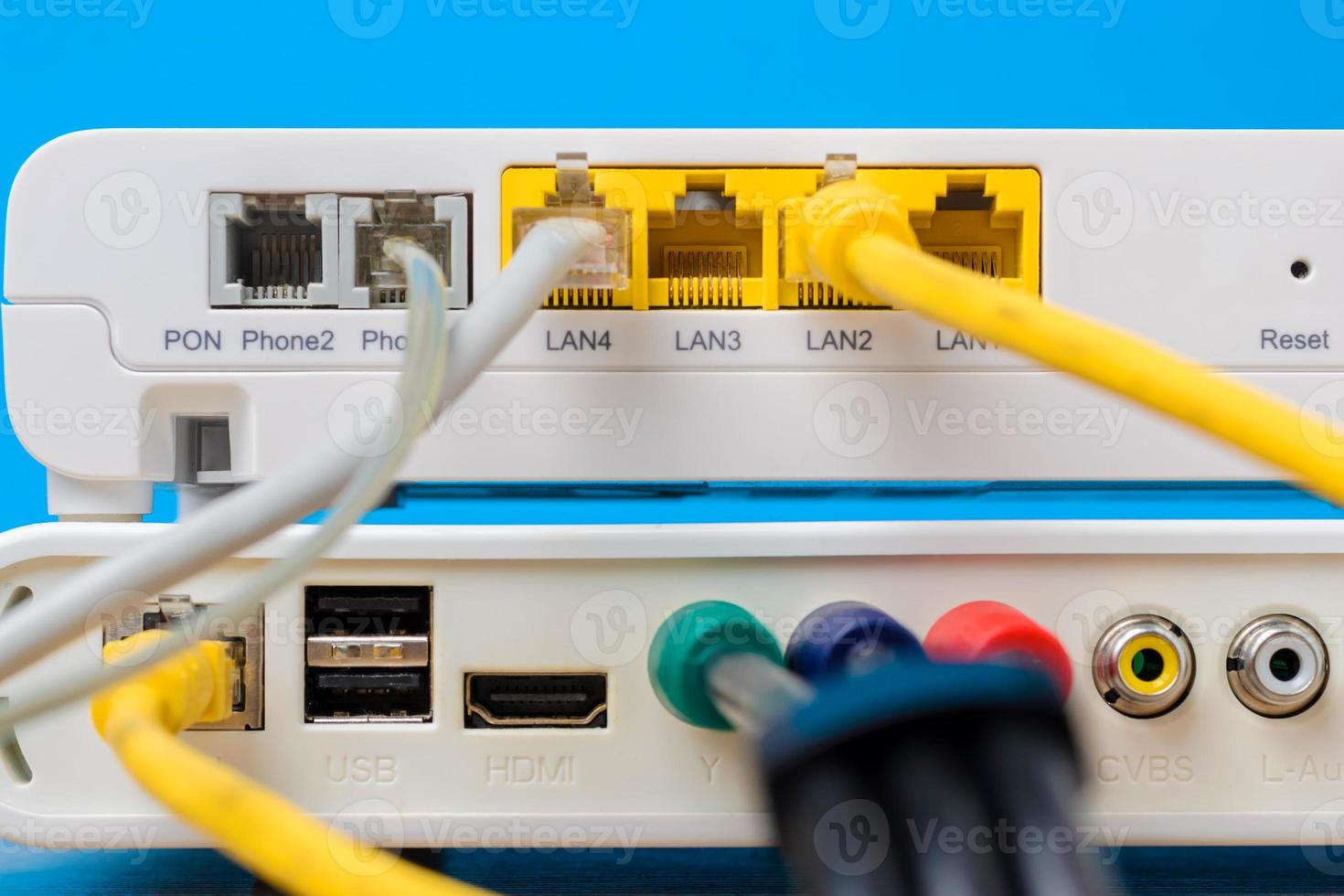 home wireless router with ethernet cables plugged in on blue background, closeup photo