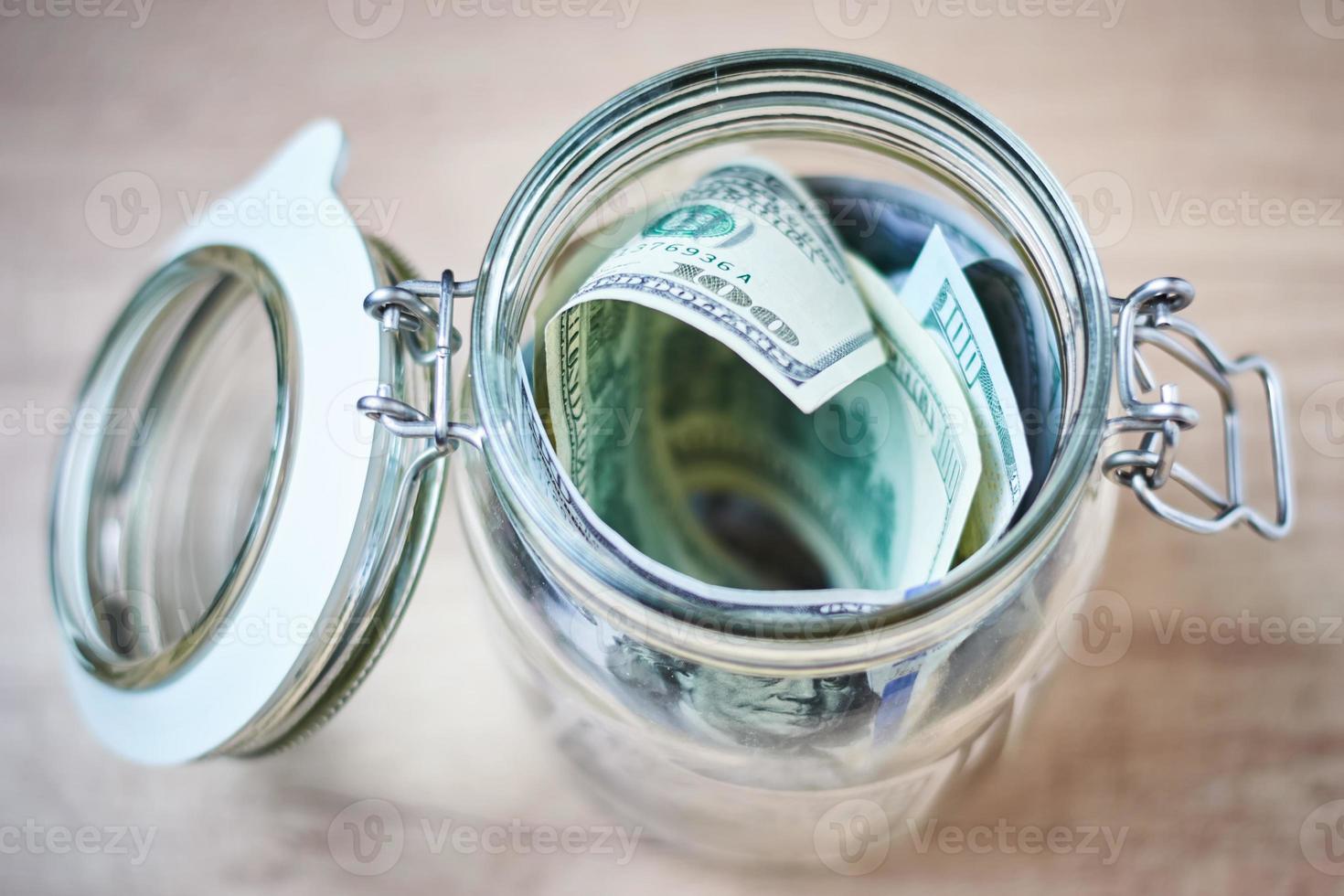 US Dollar bills in a glass jar on wooden background. Saving money and investment concept photo