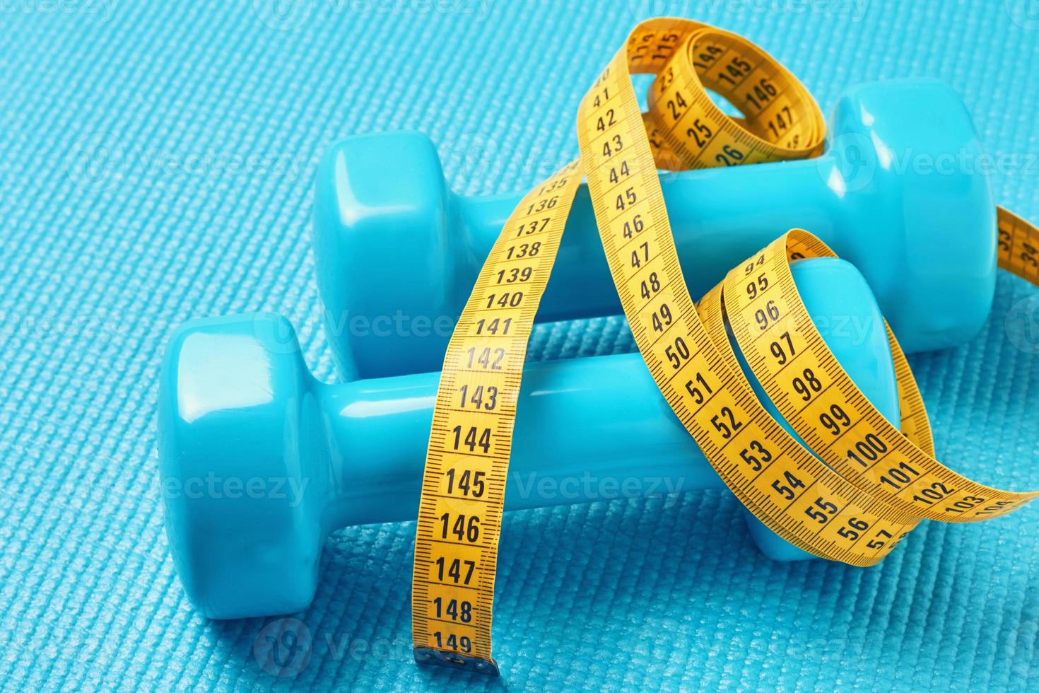 concepto de fitness. pesas y cinta métrica sobre un fondo azul, de cerca foto