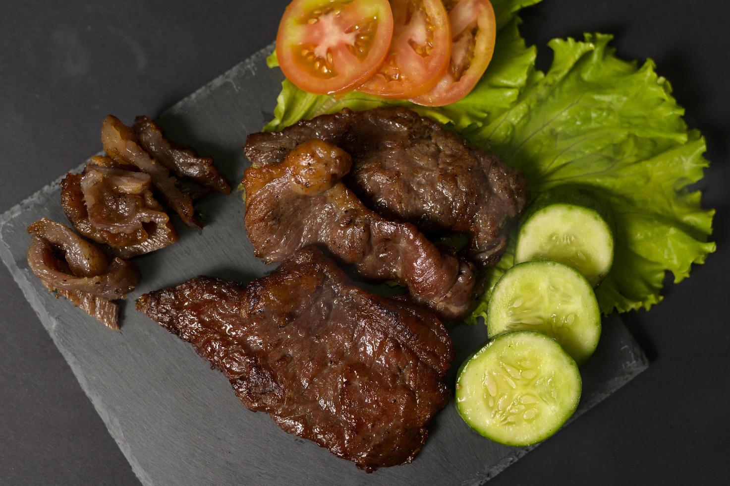 Carne de res a la parrilla en un plato sobre un estudio de fondo negro foto