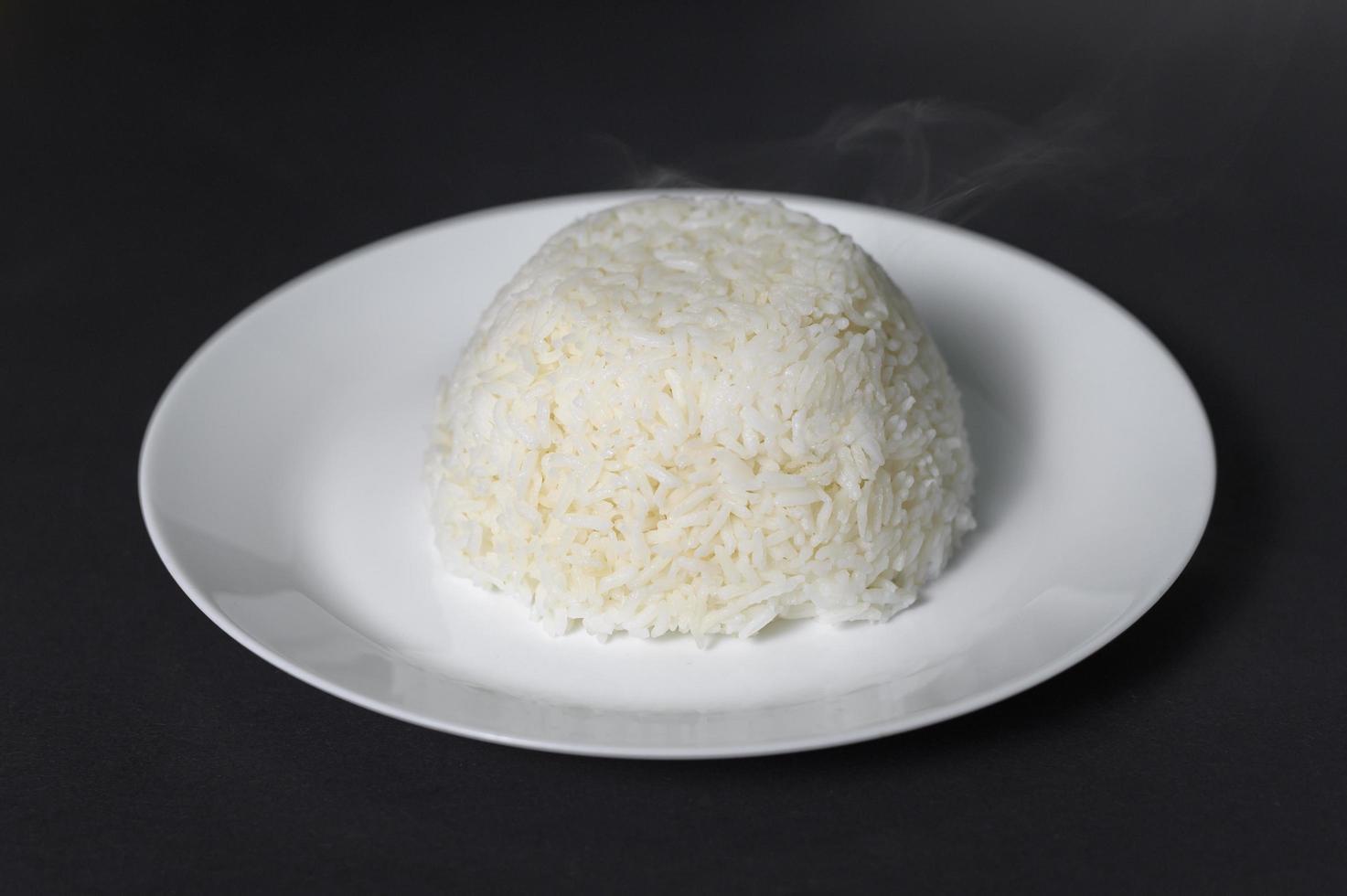 rice on white plate over black background studio photo
