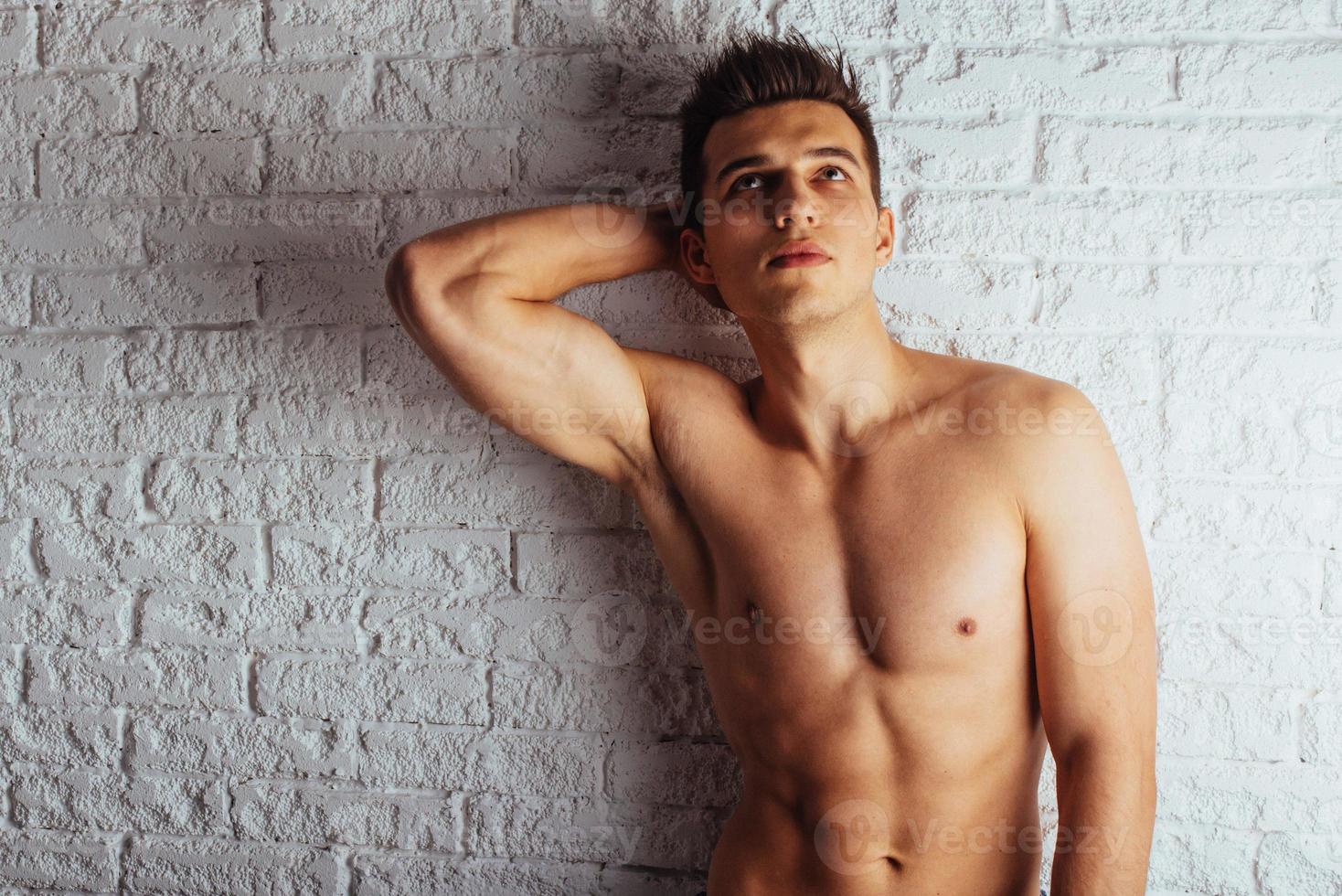 Healthy young guy posing near a white wall photo