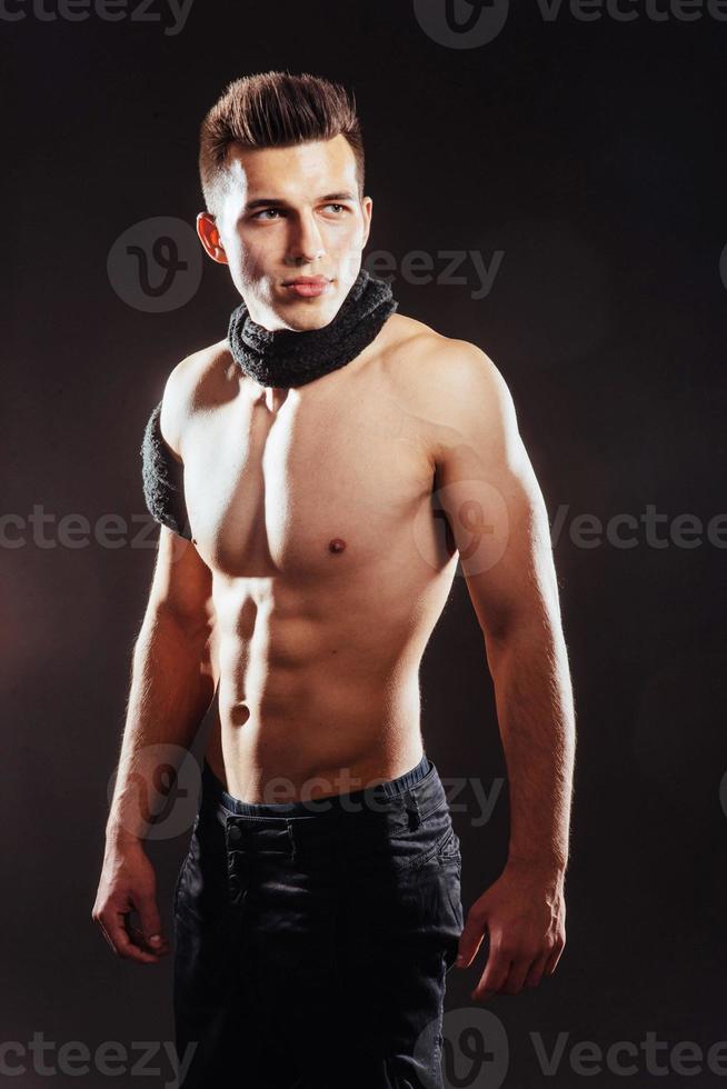 Sexy young man with a naked torso on dark background . photo