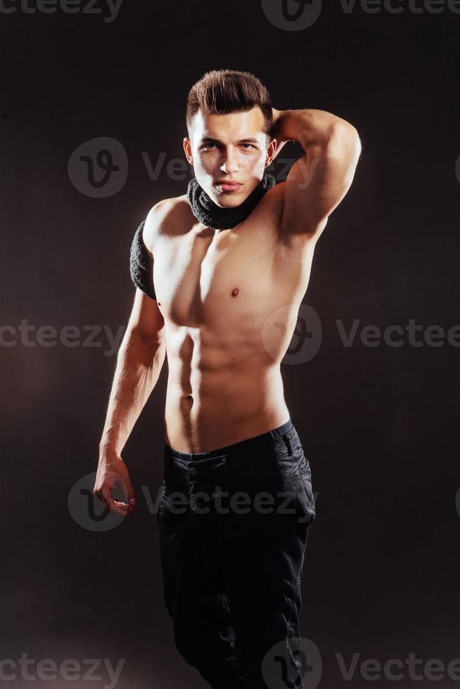 Sexy young man with a naked torso on dark background . photo