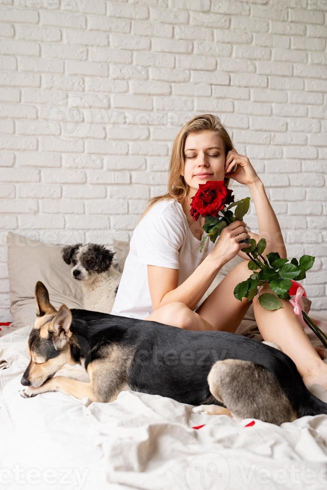 mujer sentada en la cama con su perro gracioso en casa y oliendo flores foto