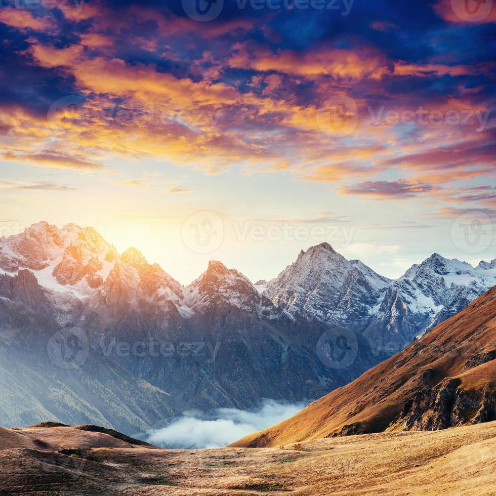 Autumn landscape and snowy mountain peaks. Fantastic sunset. Vie photo