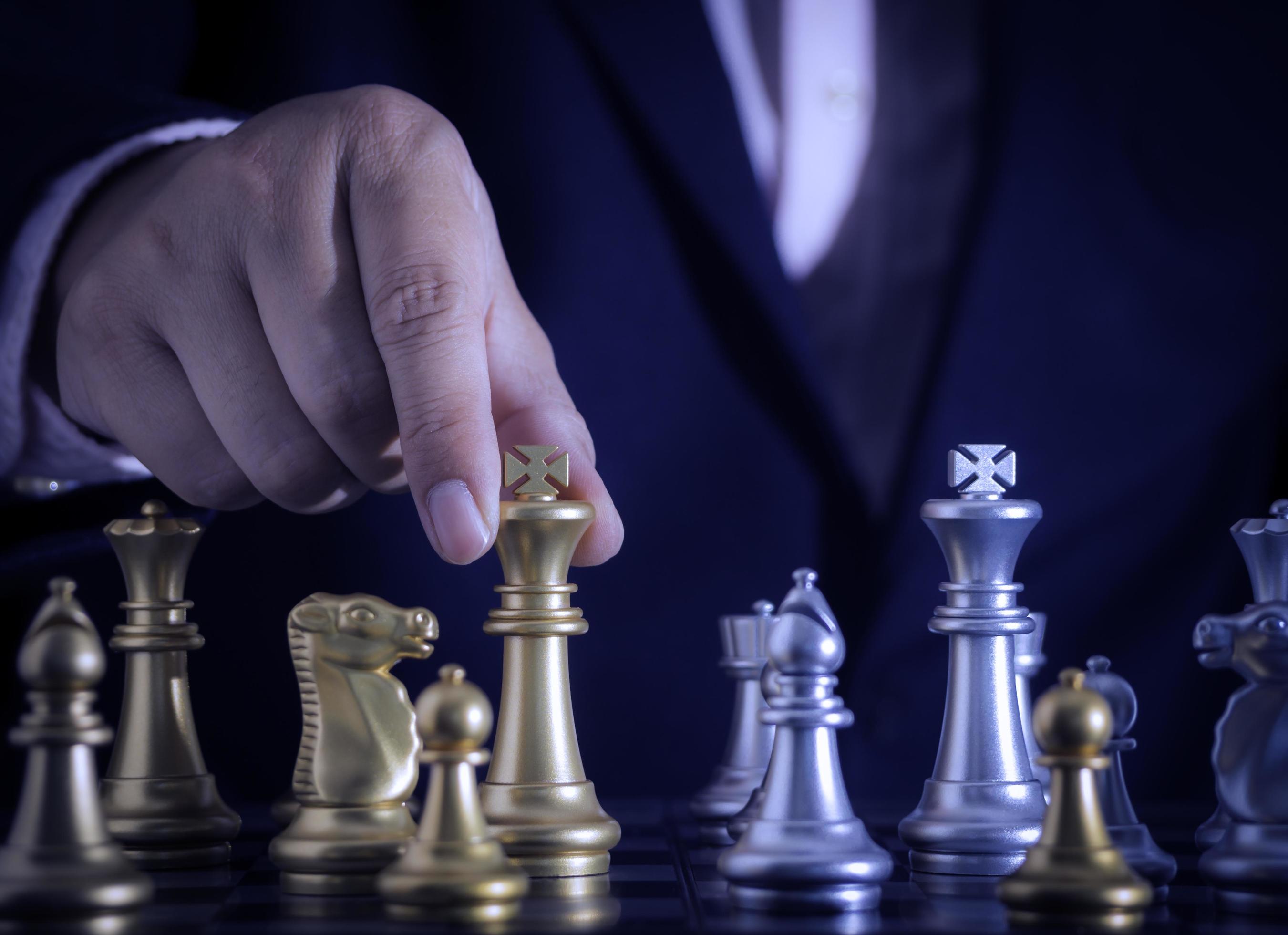 Close up of hands of a business man moving king golden chess to defeat  opponent the chess game is development analysis, strategy, and plan, the  management or leadership concept. 22804709 Stock Photo