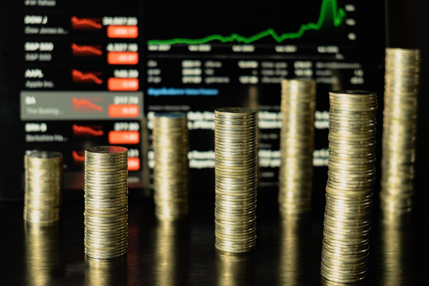 Stack of coins in different positions in front of the tablet, stock trading concept. photo
