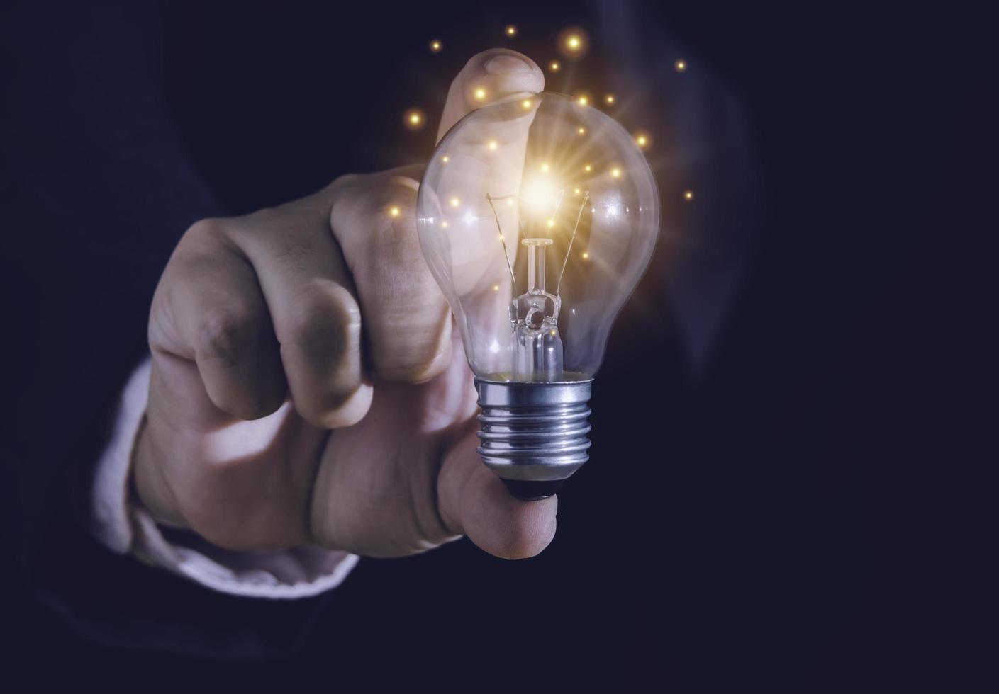 Hand of businessman holding light bulb with fire spark shine glitter for new idea with innovation and inspiration, communication and technology in science concept. photo