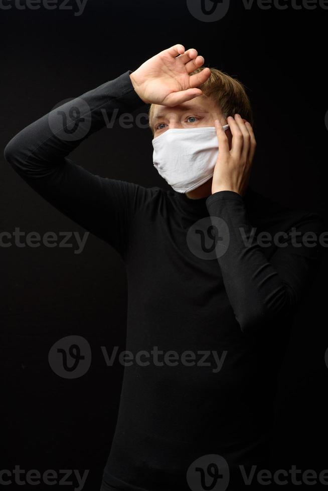 un hombre de mediana edad con un retrato de mascarilla médica de cerca ilustra la enfermedad del coronavirus pandémico en un fondo oscuro. concepto de contaminación por brotes de covid-19. foto