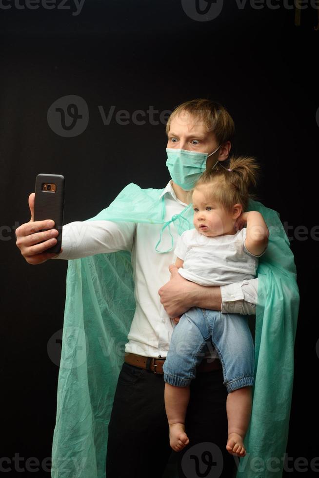 father in a medical mask holds his little daughter. The concept of protecting children during the epidemic of coronavirus photo