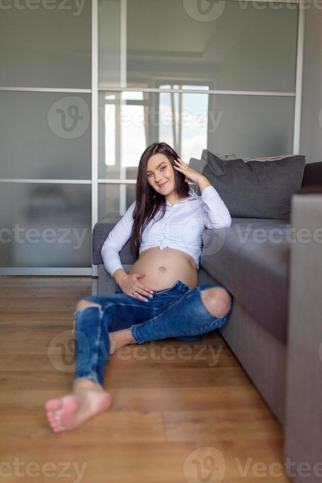 A man and a pregnant woman are sitting hugging on the couch. photo