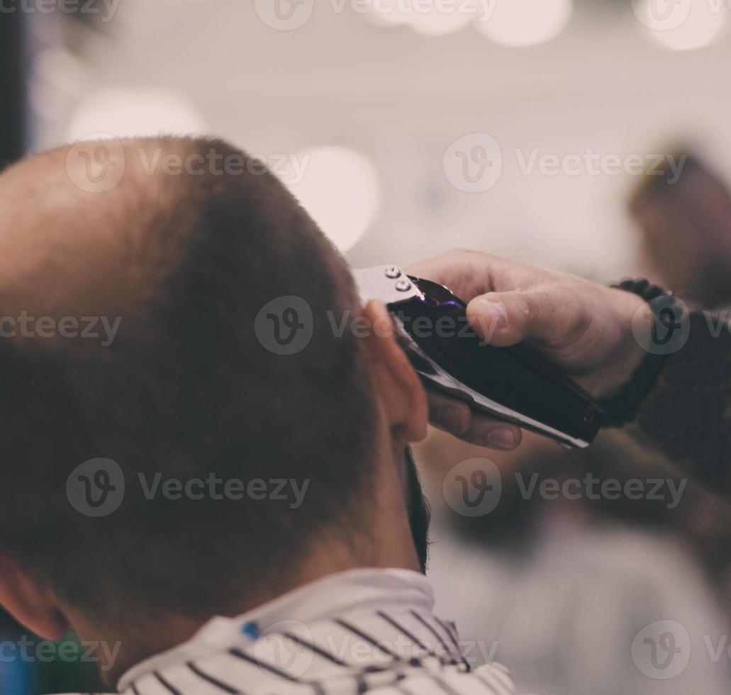 Barber cuts the hair of a young man photo