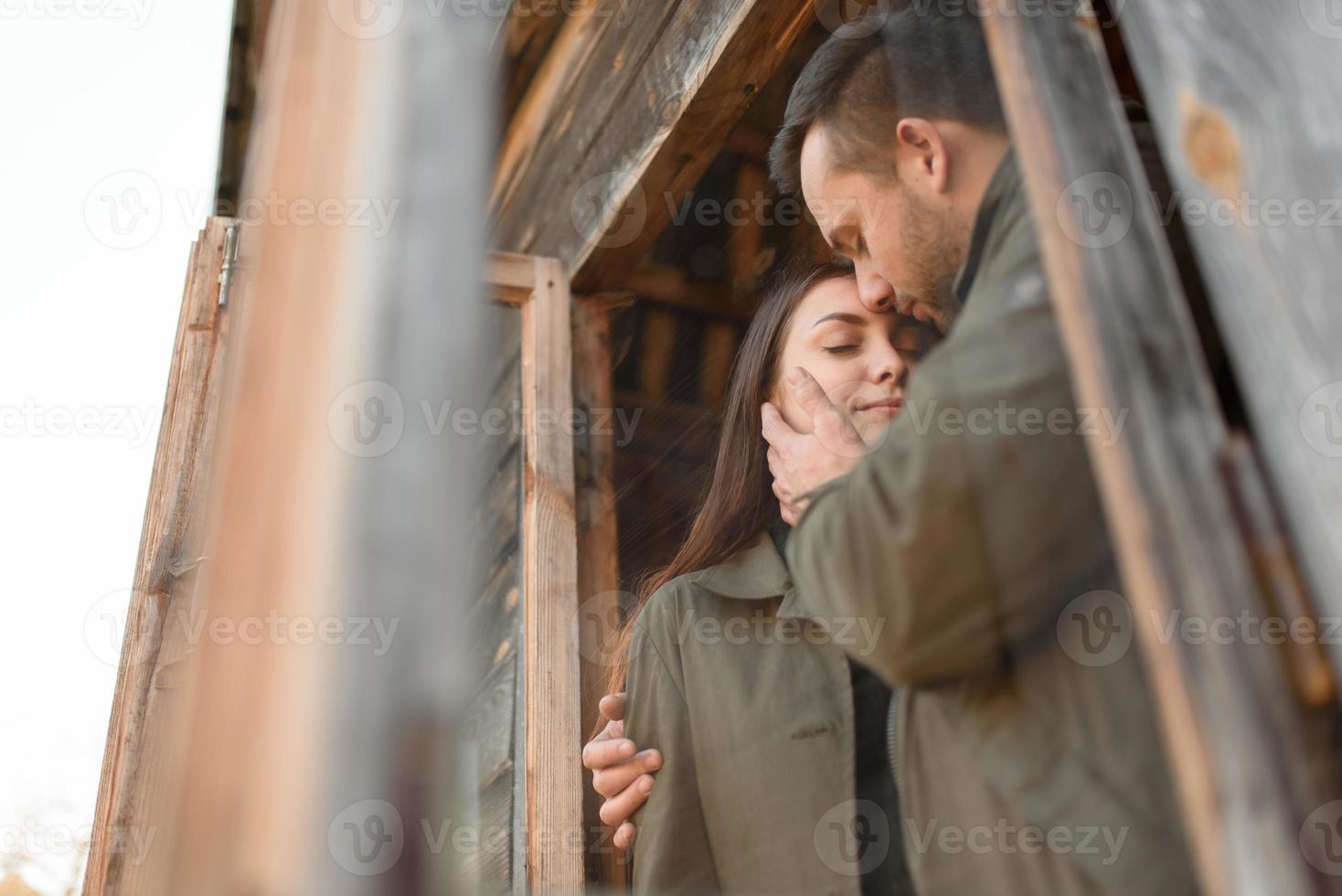 pareja enamorada mira por la ventana, casa de madera. el concepto de compra de nuevas viviendas para familias jóvenes. foto