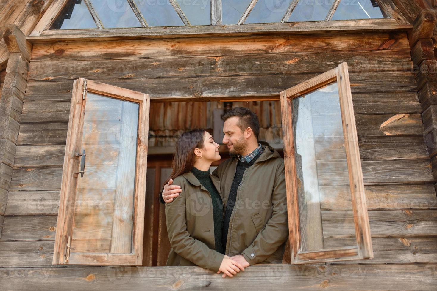 couple in love looks out of the window, wooden house. The concept of buying new housing for young families. photo